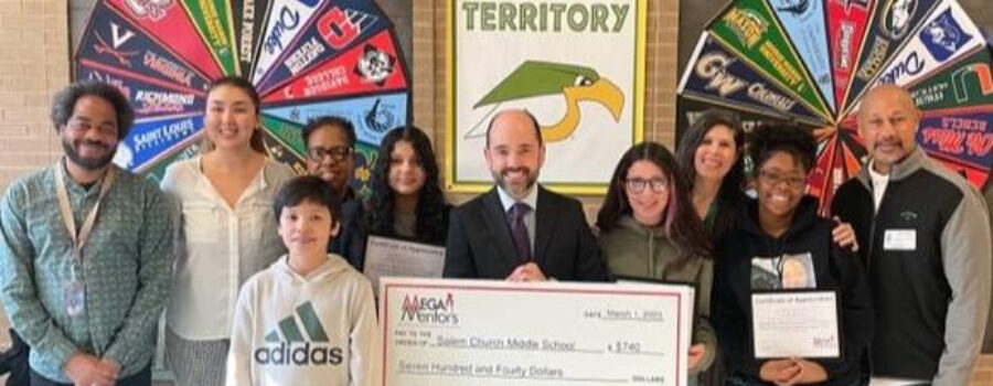 A group of students and school faculty pose with an oversized check from MEGA Mentors.